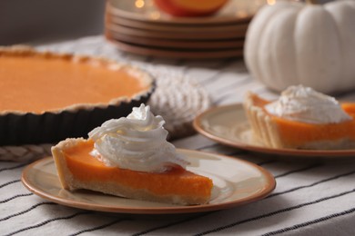 Piece of fresh homemade pumpkin pie with whipped cream on table