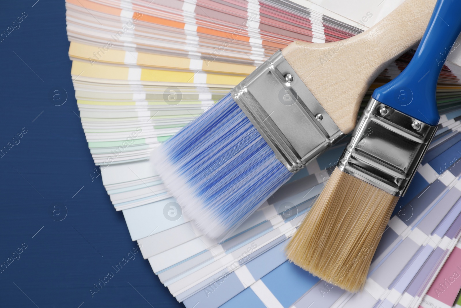 Photo of Paint brushes and palette on blue wooden table, top view