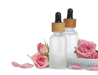 Photo of Bottles of essential rose oils and flowers on white background