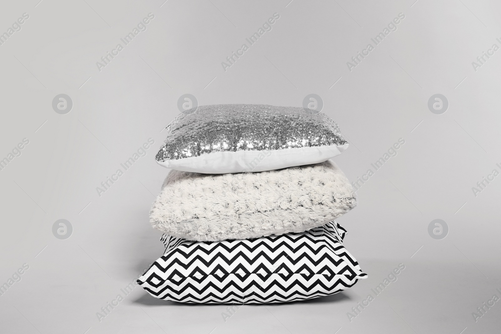 Photo of Stylish decorative pillows stacked on light background