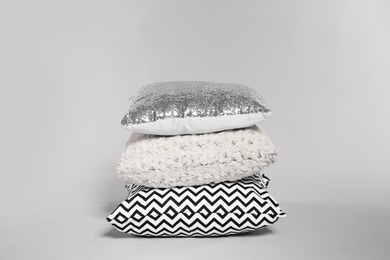 Stylish decorative pillows stacked on light background