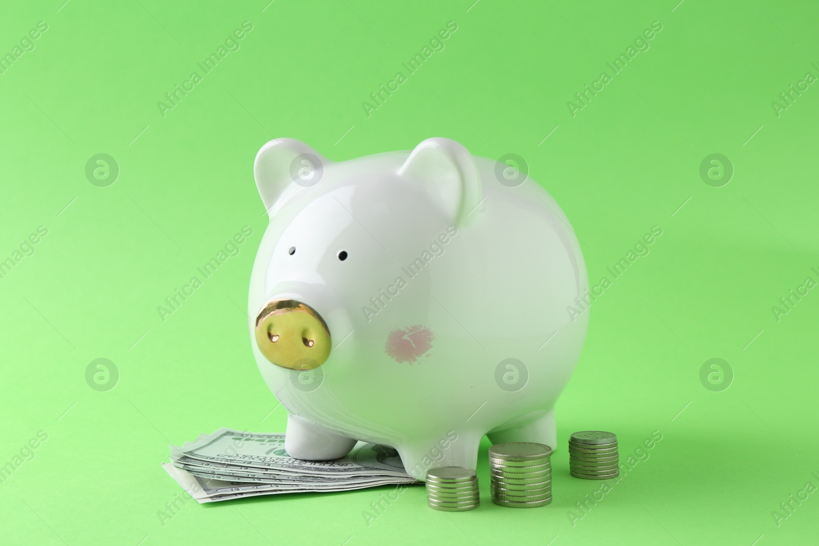 Photo of Financial savings. Piggy bank, dollar banknotes and stacked coins on green background