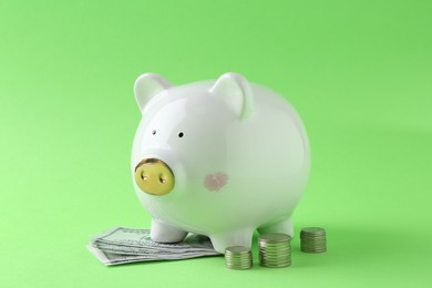 Photo of Financial savings. Piggy bank, dollar banknotes and stacked coins on green background