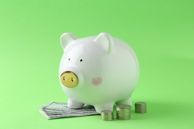 Financial savings. Piggy bank, dollar banknotes and stacked coins on green background