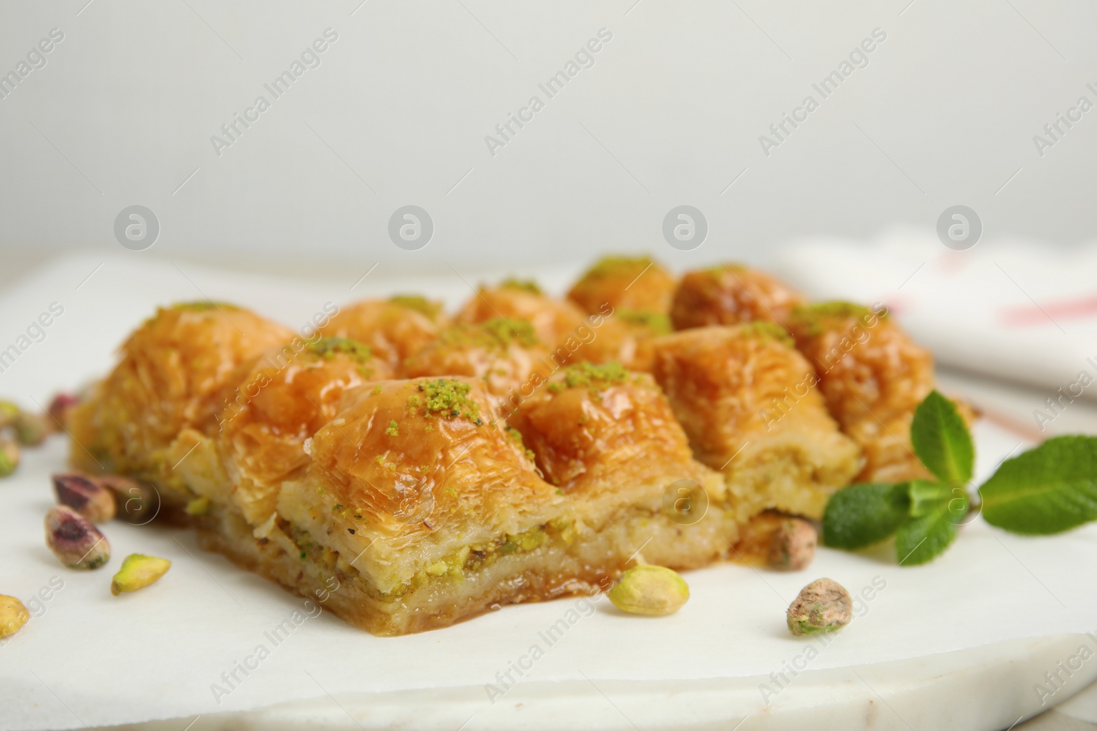 Photo of Delicious sweet baklava with pistachios and mint on board, closeup