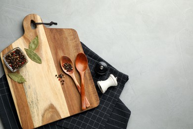 Cutting board and condiments on grey table, flat lay with space for text. Cooking utensils