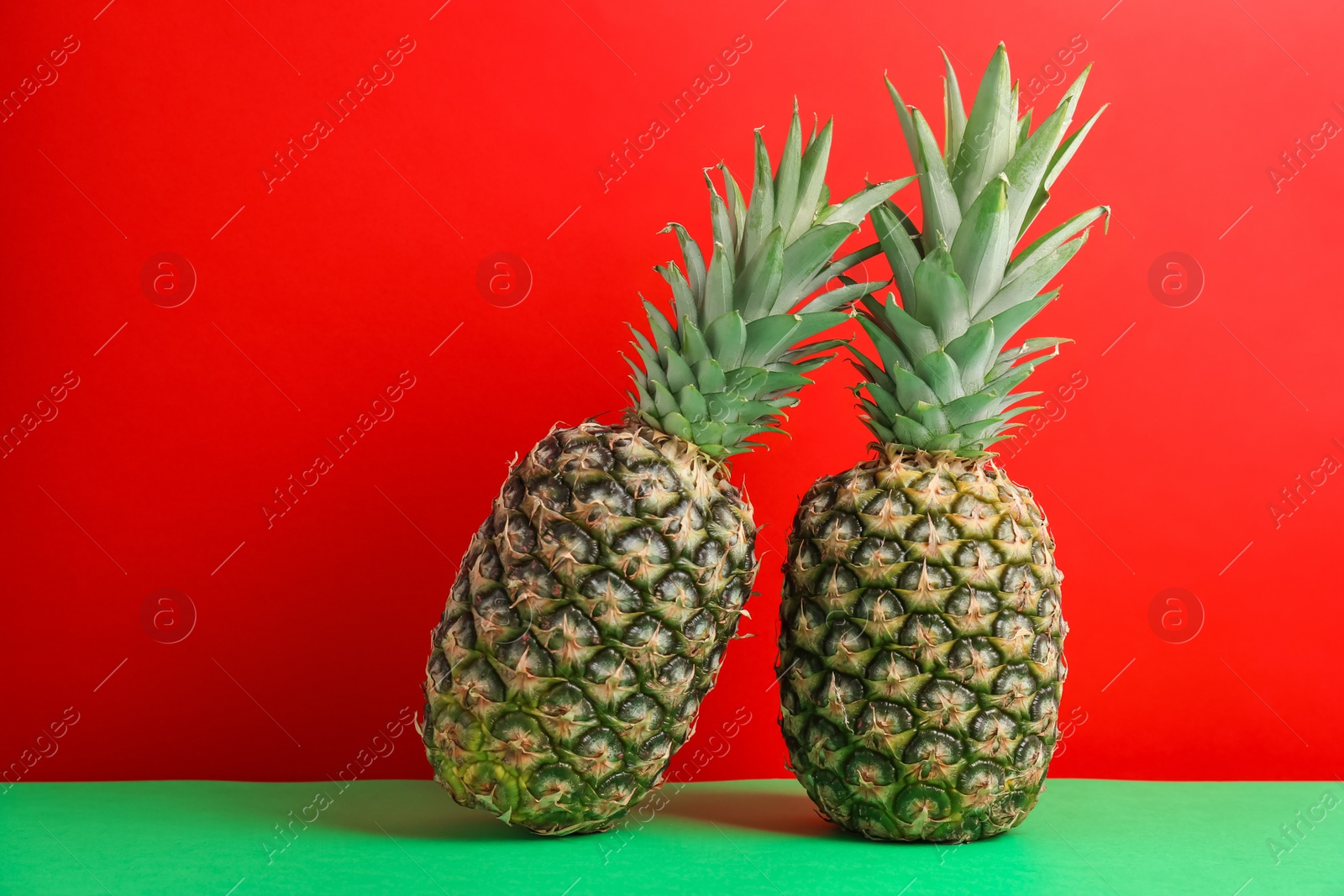 Photo of Fresh pineapples on table against color wall