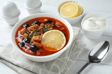 Meat solyanka soup with sausages, olives and vegetables served on white wooden table