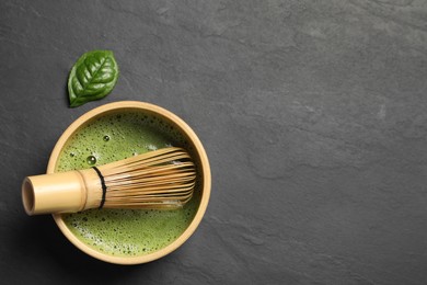 Cup of fresh matcha tea with bamboo whisk on black table, flat lay. Space for text