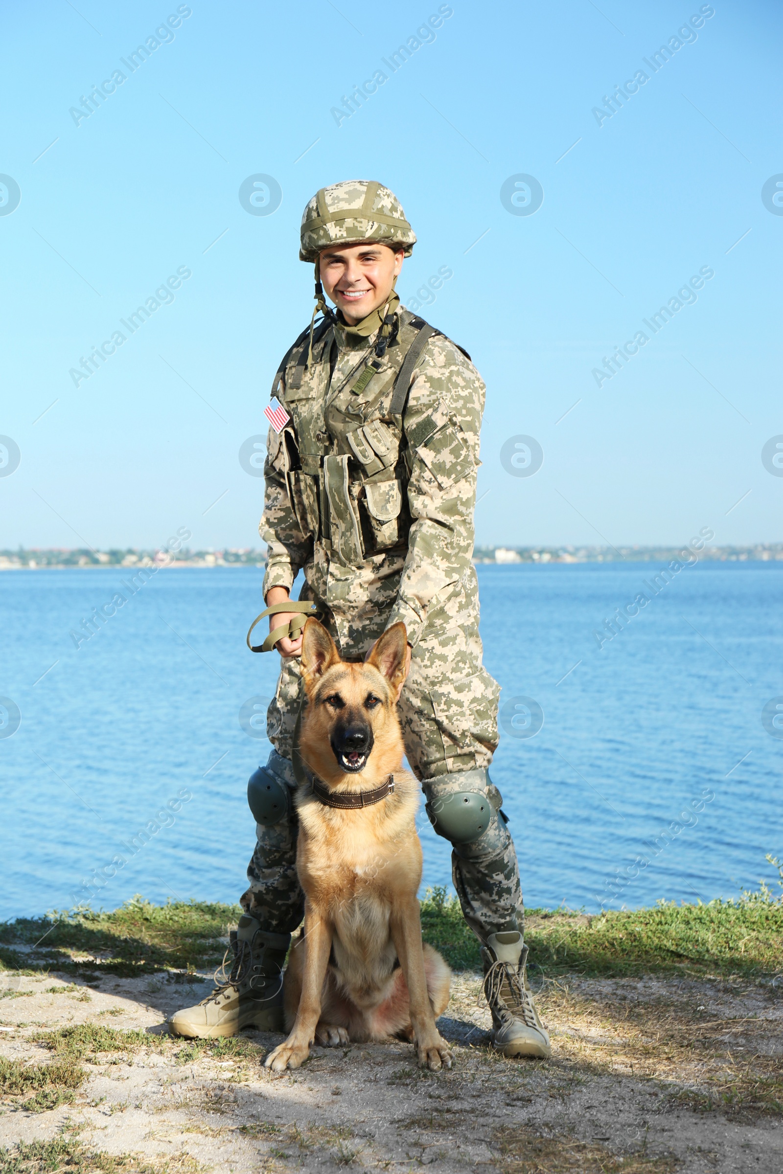 Photo of Man in military uniform with German shepherd dog near river