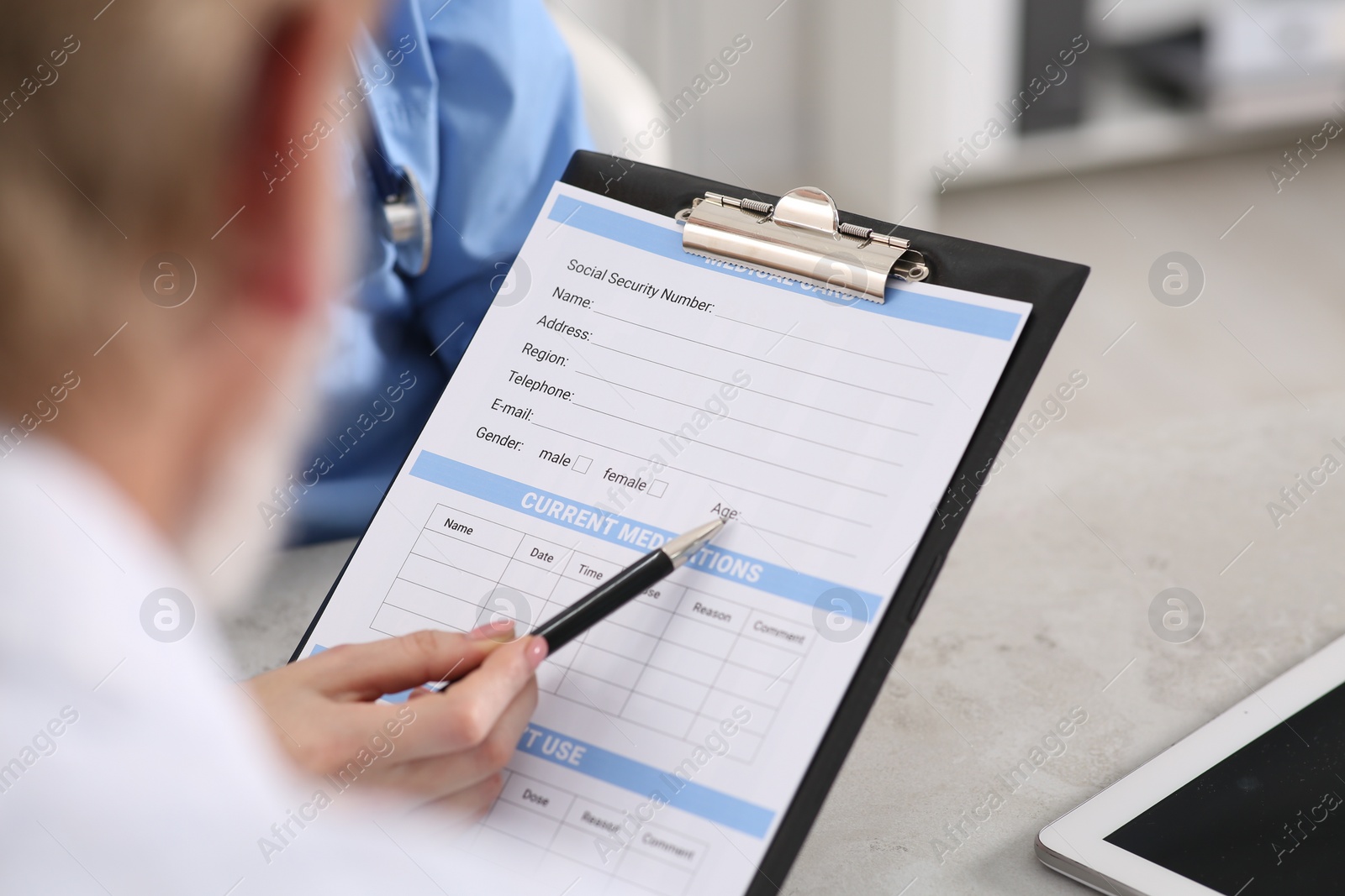 Photo of Doctor showing medical card to patient at table in clinic, closeup