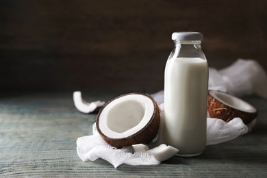 Photo of Bottle of coconut milk and nuts on wooden table, space for text