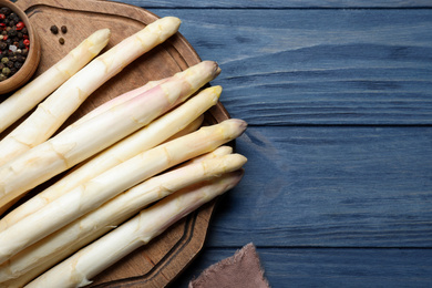 Fresh white asparagus on blue wooden table, flat lay. Space for text