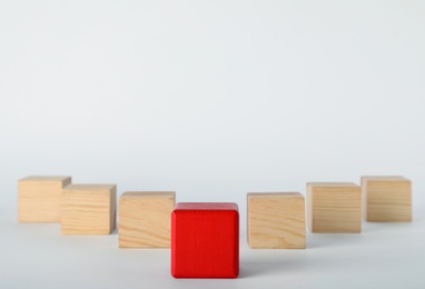 Photo of Red cube in front of wooden ones on white background. Victory concept