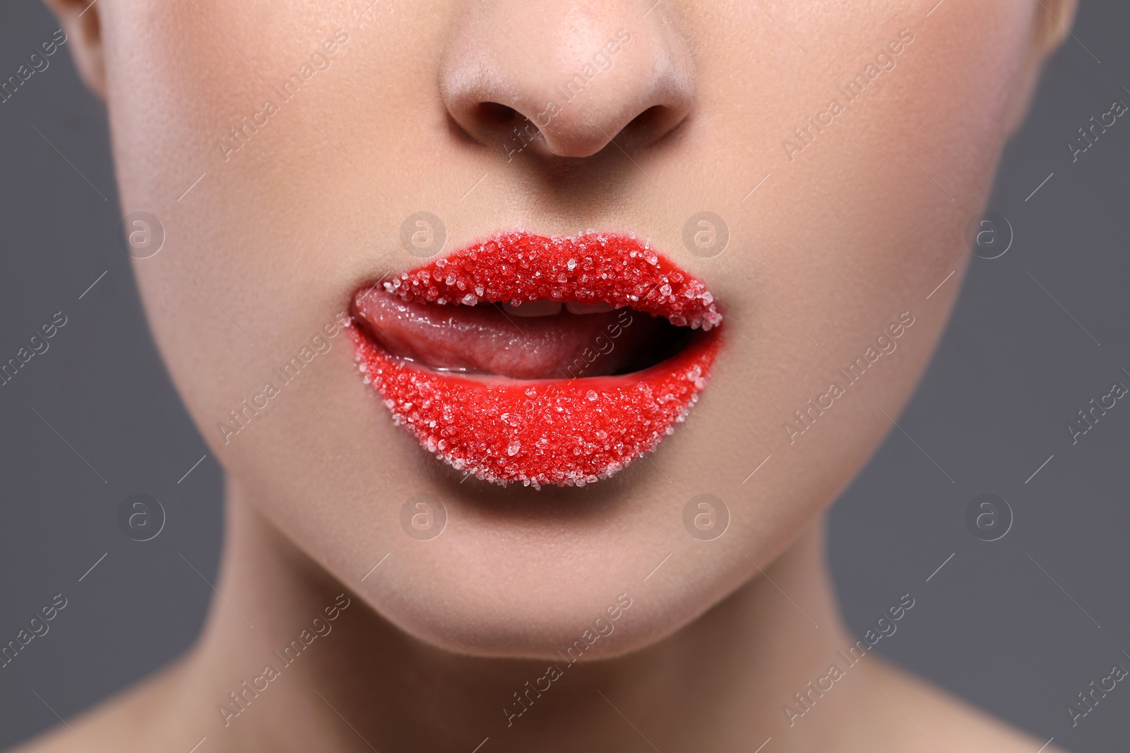Photo of Woman with beautiful lips covered in sugar on grey background, closeup