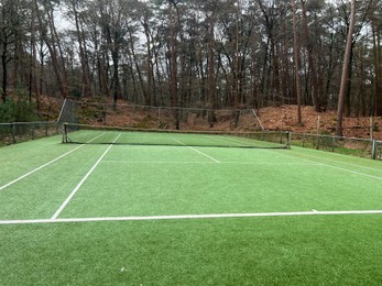 Photo of Tennis court with artificial grass and net outdoors