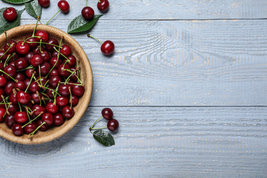 Photo of Sweet juicy cherries on blue wooden table, flat lay. Space for text