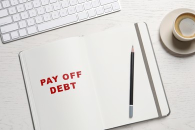 Notebook with phrase Pay Off Debt, pencil, coffee and keyboard on white wooden table, flat lay