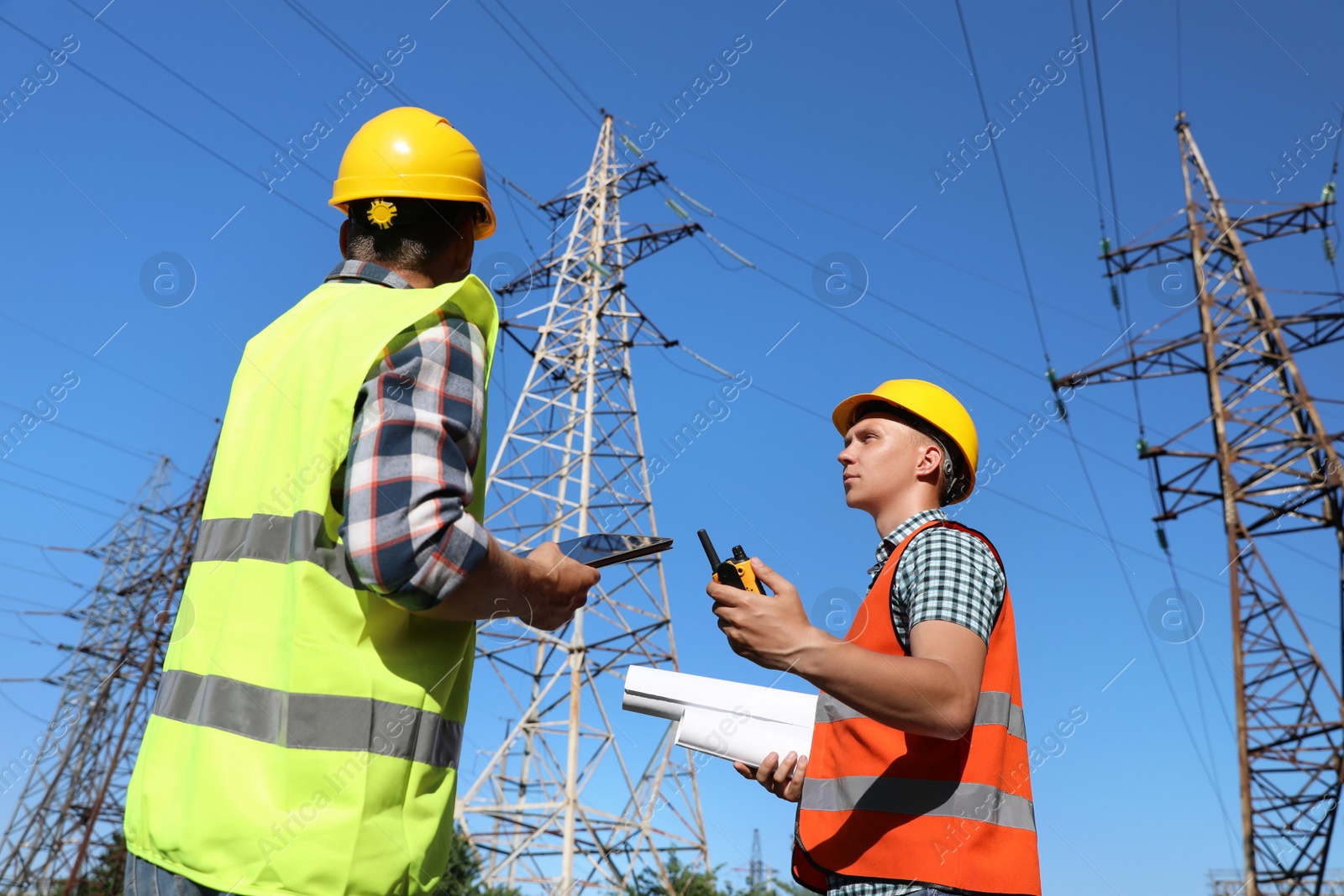 Photo of Professional electricians in uniforms near high voltage towers