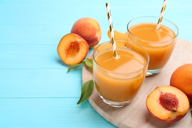 Photo of Natural peach juice and fresh fruits on light blue wooden table. Space for text