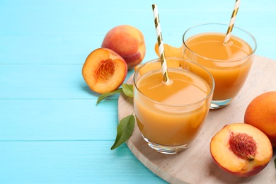 Natural peach juice and fresh fruits on light blue wooden table. Space for text