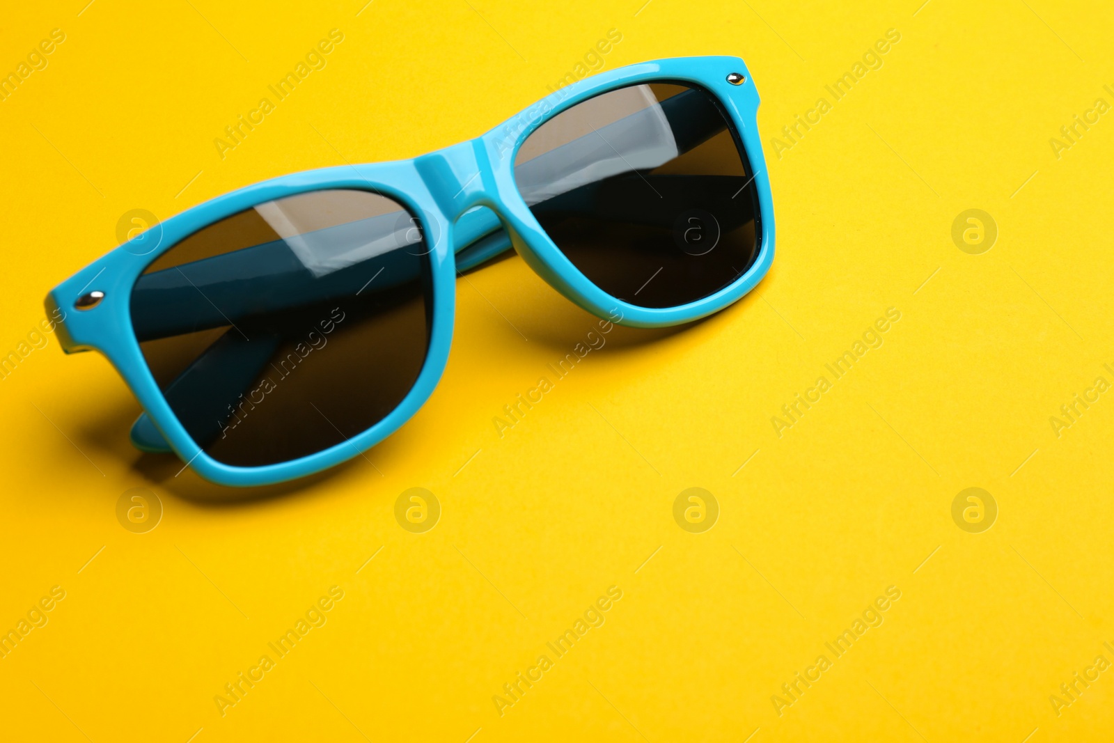 Photo of Stylish sunglasses on yellow background, space for text. Fashionable accessory