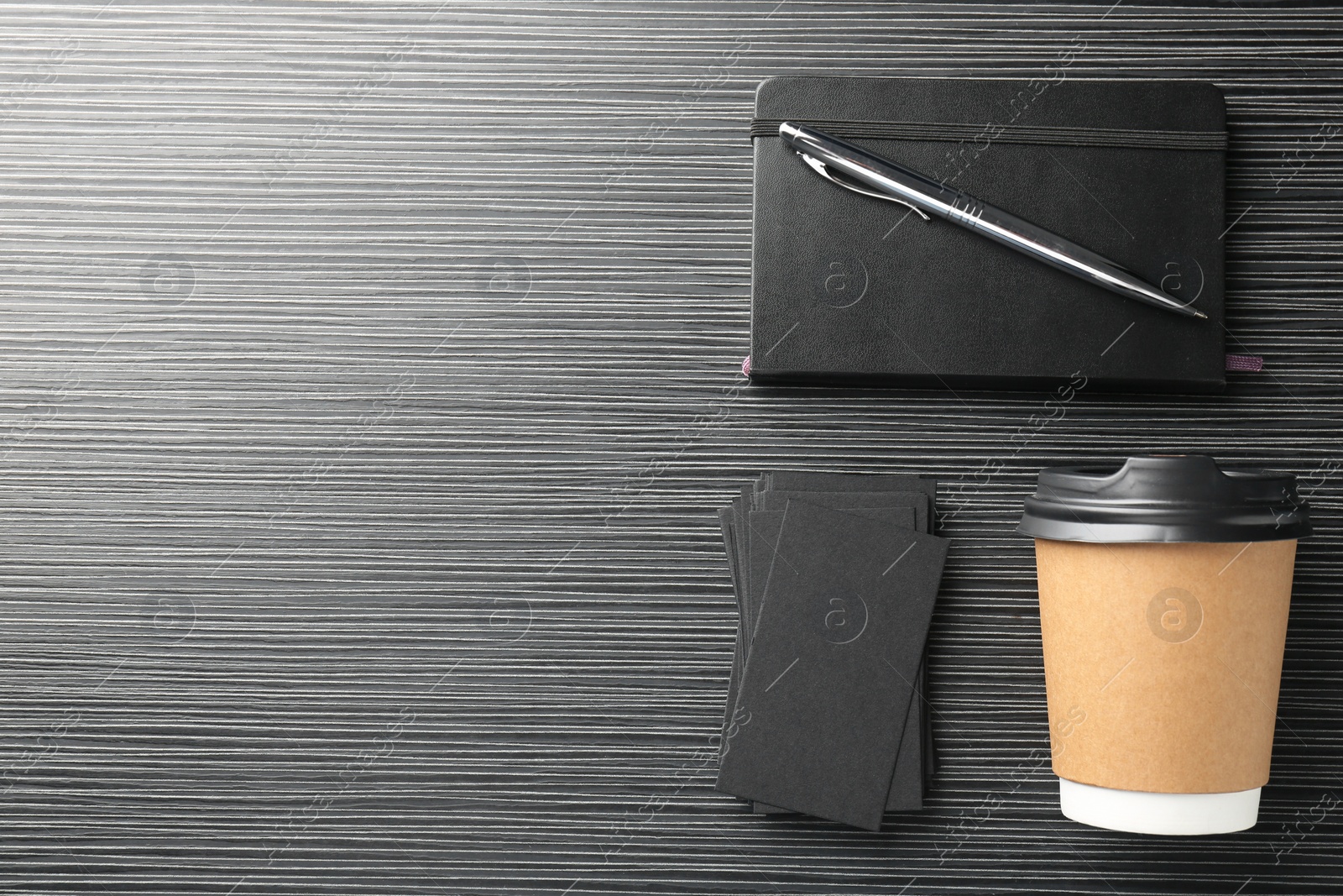 Photo of Blank black business cards, paper cup of coffee and stationery on wooden table, flat lay. Mockup for design