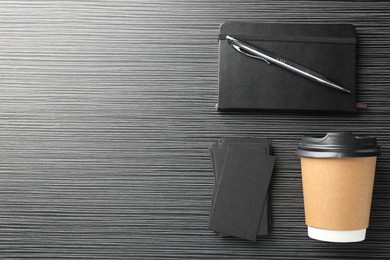 Blank black business cards, paper cup of coffee and stationery on wooden table, flat lay. Mockup for design