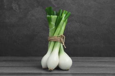 Photo of Bunch of green spring onions on grey wooden table