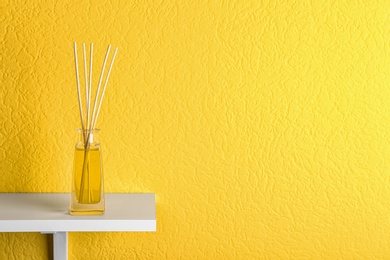 Reed air freshener on table against yellow background, space for text