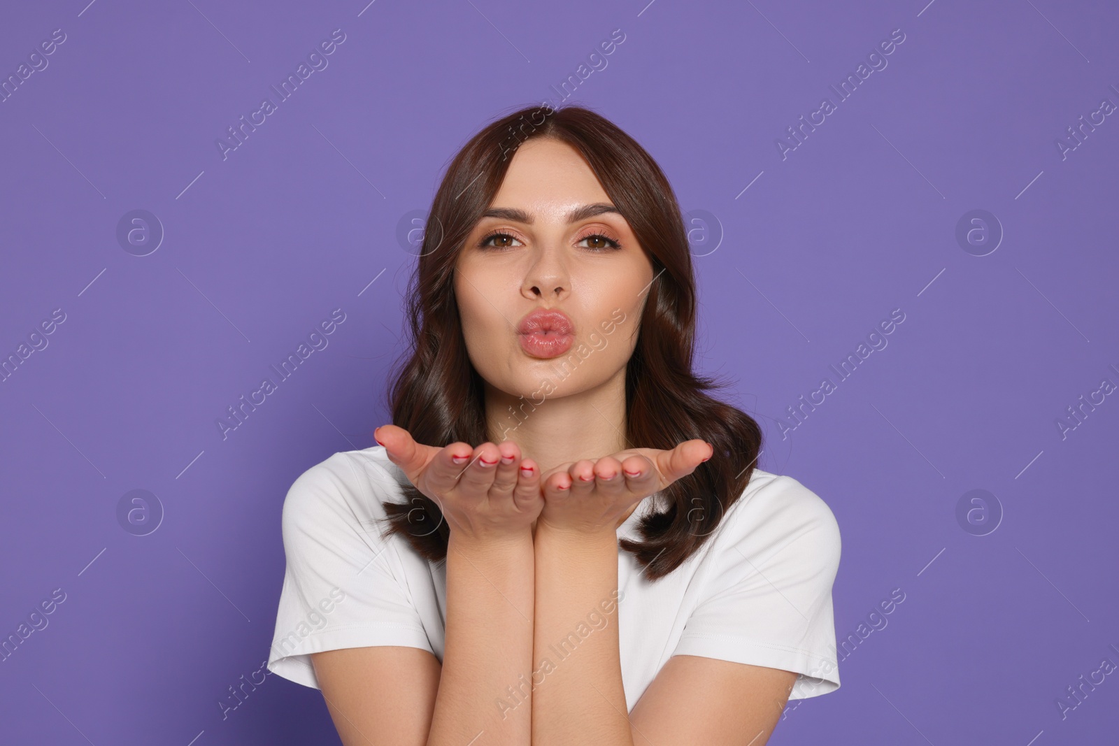 Photo of Beautiful young woman blowing kiss on purple background