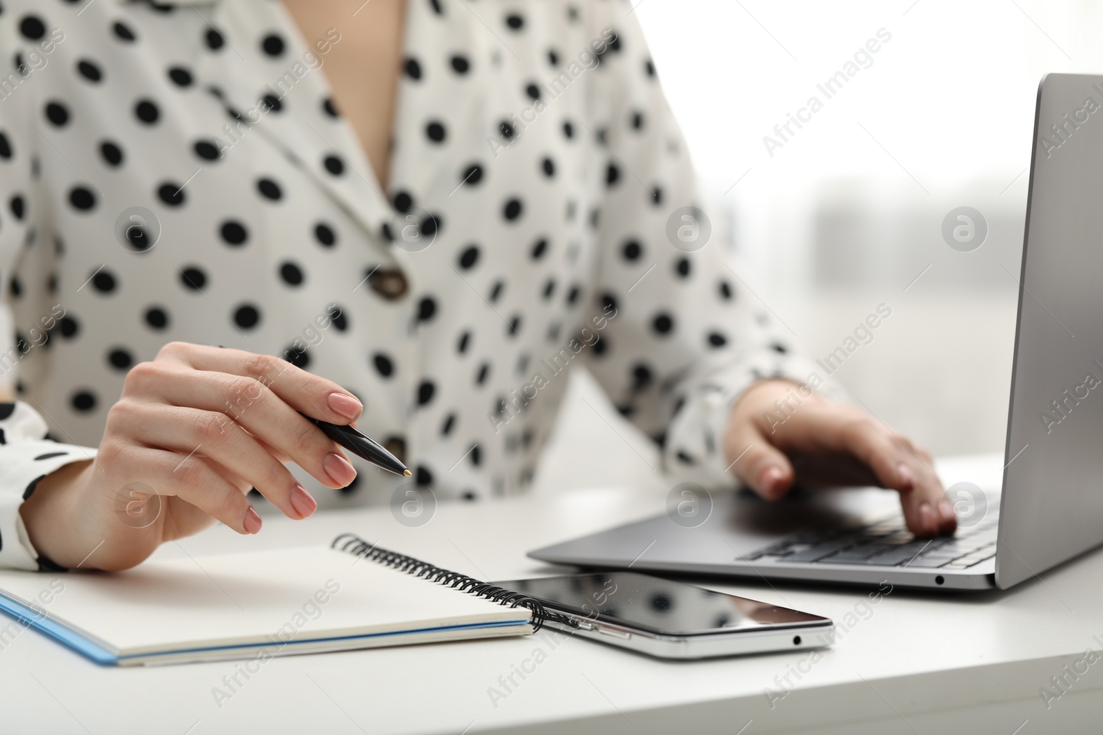 Photo of E-learning. Woman taking notes during online lesson at table indoors, closeup