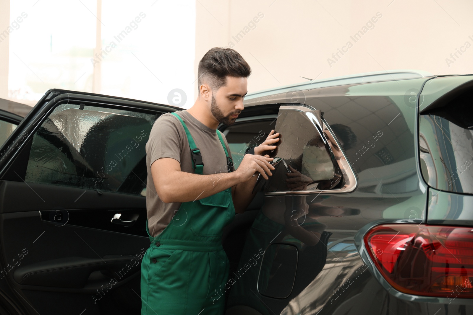 Photo of Worker tinting car window with foil in workshop