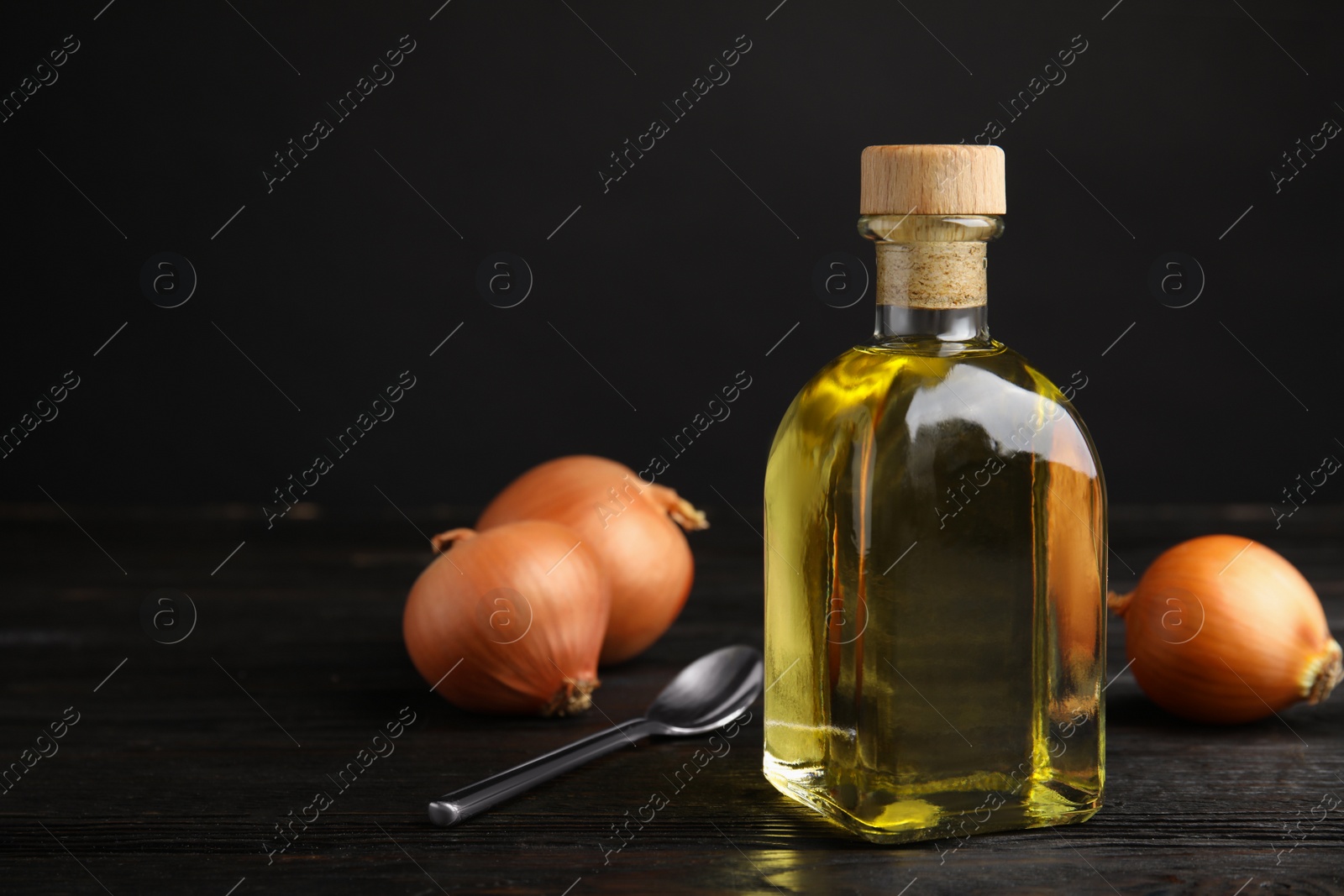 Photo of Glass bottle of onion syrup and fresh vegetable on dark background. Space for text