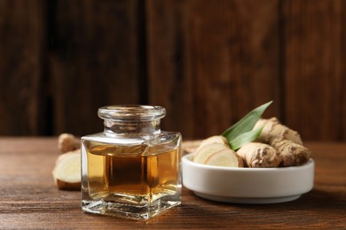 Photo of Ginger essential oil in bottle on wooden table