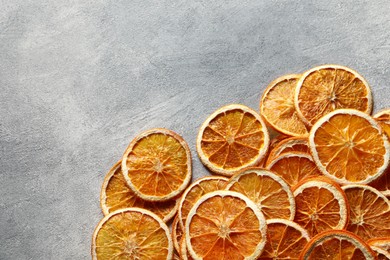 Photo of Many dry orange slices on grey textured table, top view. Space for text