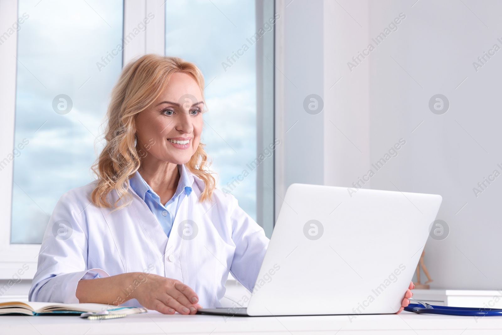 Photo of Doctor with laptop consulting patient in clinic. Online medicine concept