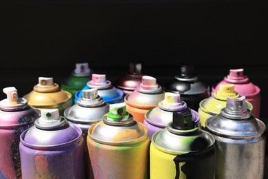Photo of Used cans of spray paint on dark background. Graffiti supplies