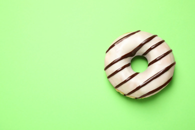 Photo of Delicious glazed donut on green background, top view. Space for text