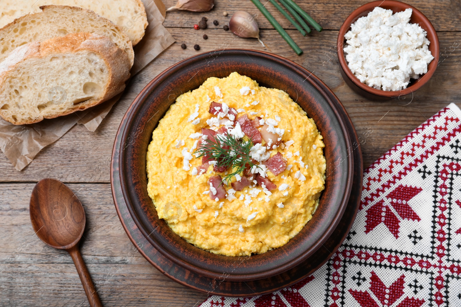 Photo of Traditional Ukrainian banosh served with brynza and pork cracklings on wooden table, flat lay