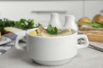 Photo of Delicious fish soup in bowl on light table, closeup