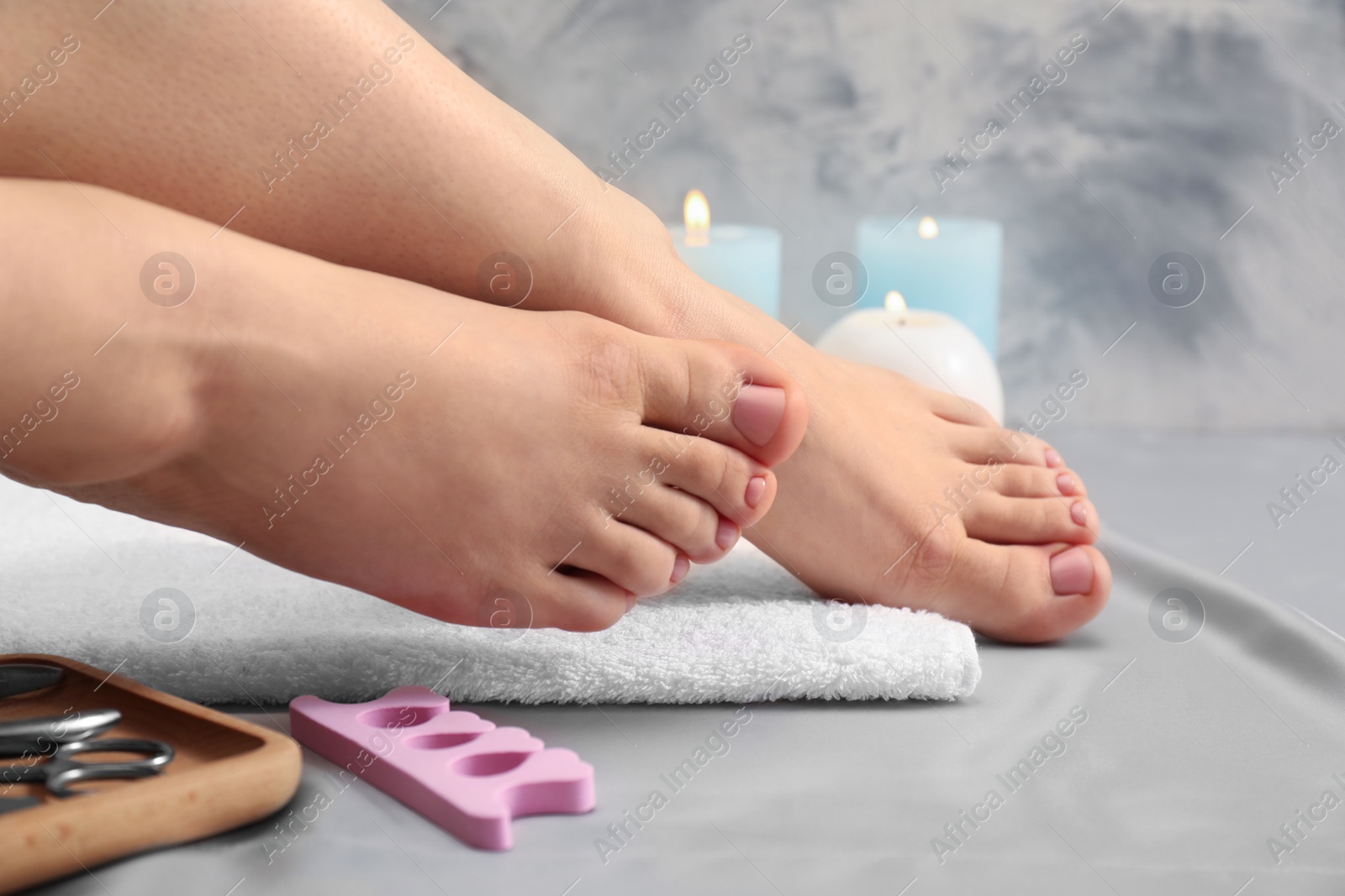 Photo of Woman with neat toenails after pedicure procedure on grey silky fabric, closeup