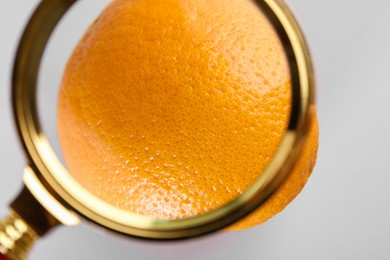 Photo of Cellulite problem. Zoomed orange on light grey background, view through magnifying glass