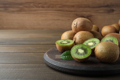 Photo of Fresh ripe kiwis on wooden table, space for text