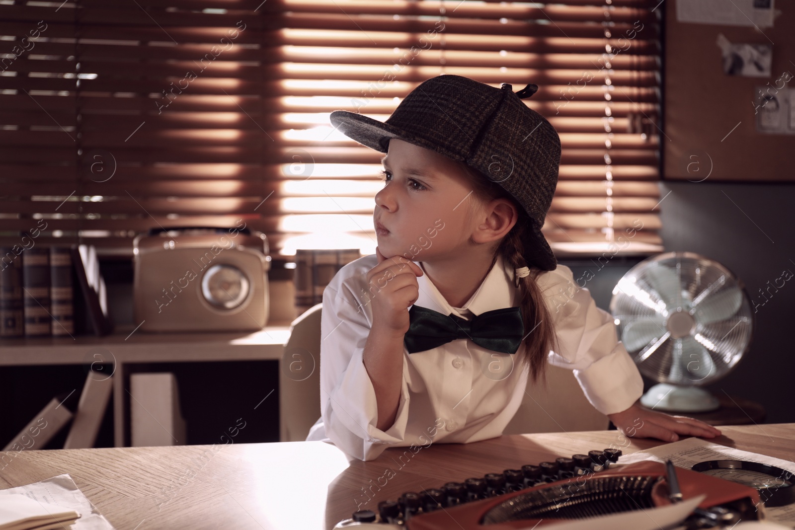 Photo of Thoughtful little detective at table in office