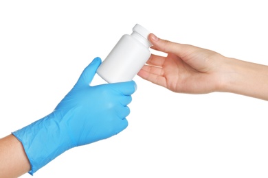 Photo of Doctor in medical glove giving bottle of pills to patient on white background