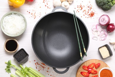 Photo of Wok, chopsticks and different products on white wooden table, flat lay