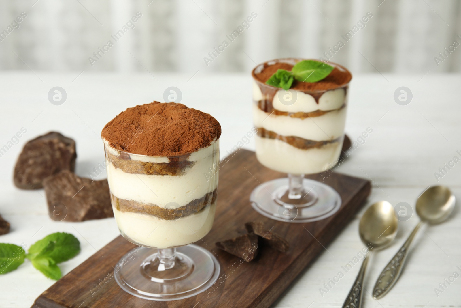 Photo of Composition with two glasses of tiramisu cake and chocolate on table