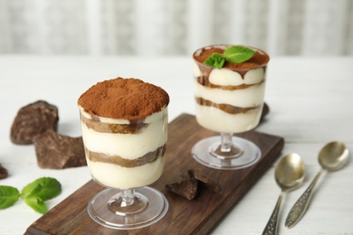 Photo of Composition with two glasses of tiramisu cake and chocolate on table