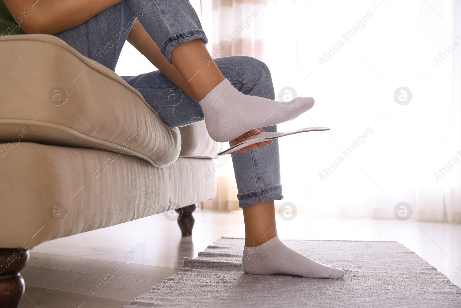 Photo of Woman fitting orthopedic insole at home, closeup